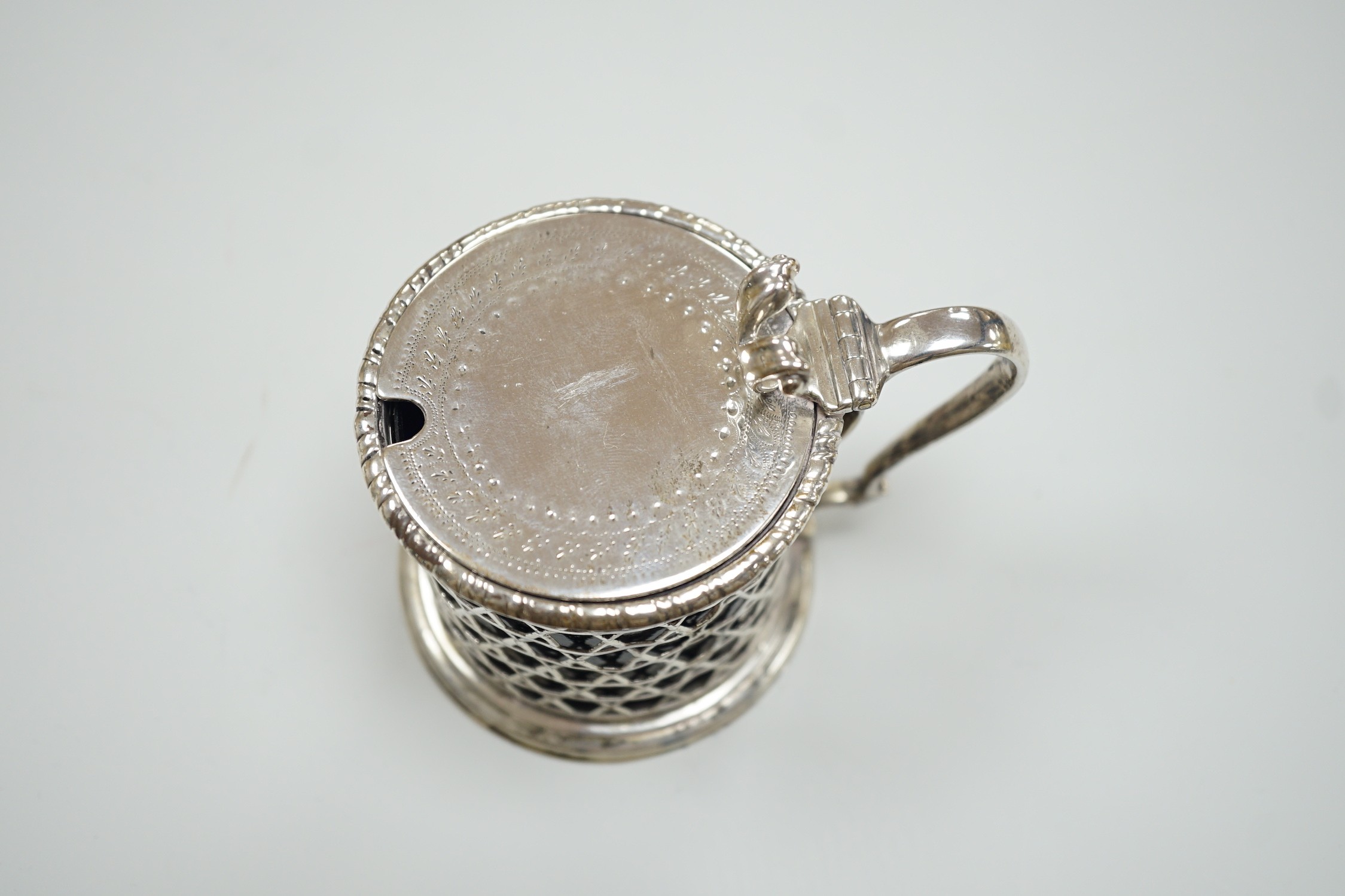 A Victorian pierced silver drum mustard pot by George Fox, London, 1872, with blue glass liner, (handle repair), height 76mm.